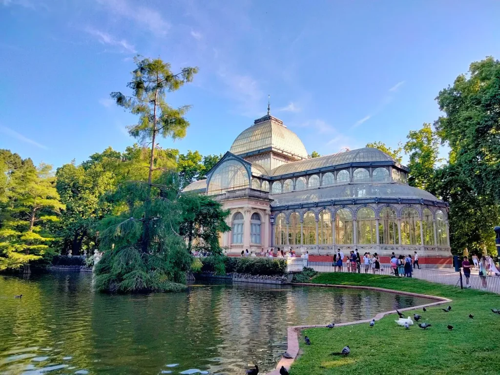 Palais de Cristal du parc du Retiro à Madrid, entouré de son étang et de sa végétation.