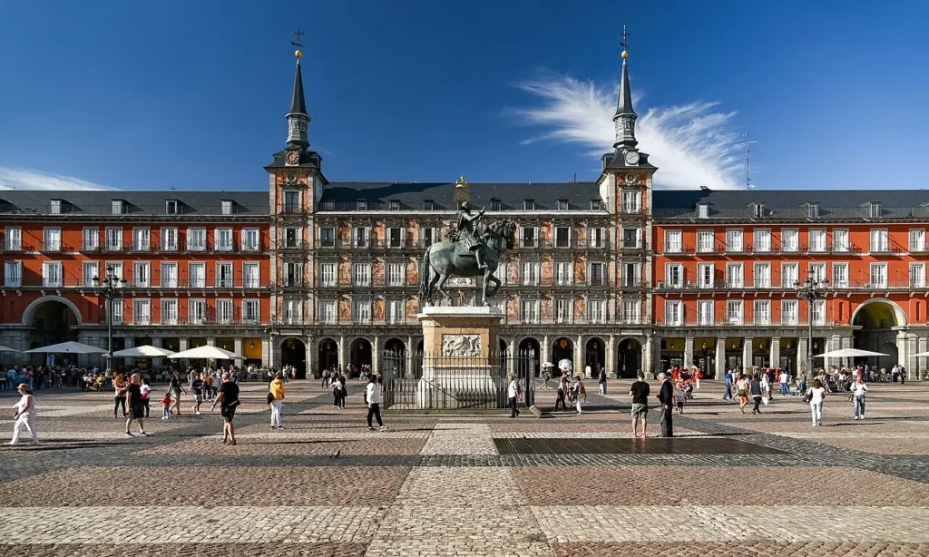 Visiter Madrid : les 15 incontournables pour un premier séjour Vue de la Plaza Mayor de Madrid entourée de ses arcades historiques et de ses bâtiments emblématiques au cœur du centre-ville.