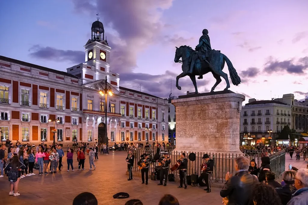 Visiter Madrid : les 15 incontournables pour un premier séjour Vue de la Puerta del Sol à Madrid avec la statue équestre de Charles III, l'une des places les plus emblématiques de la capitale espagnole.
