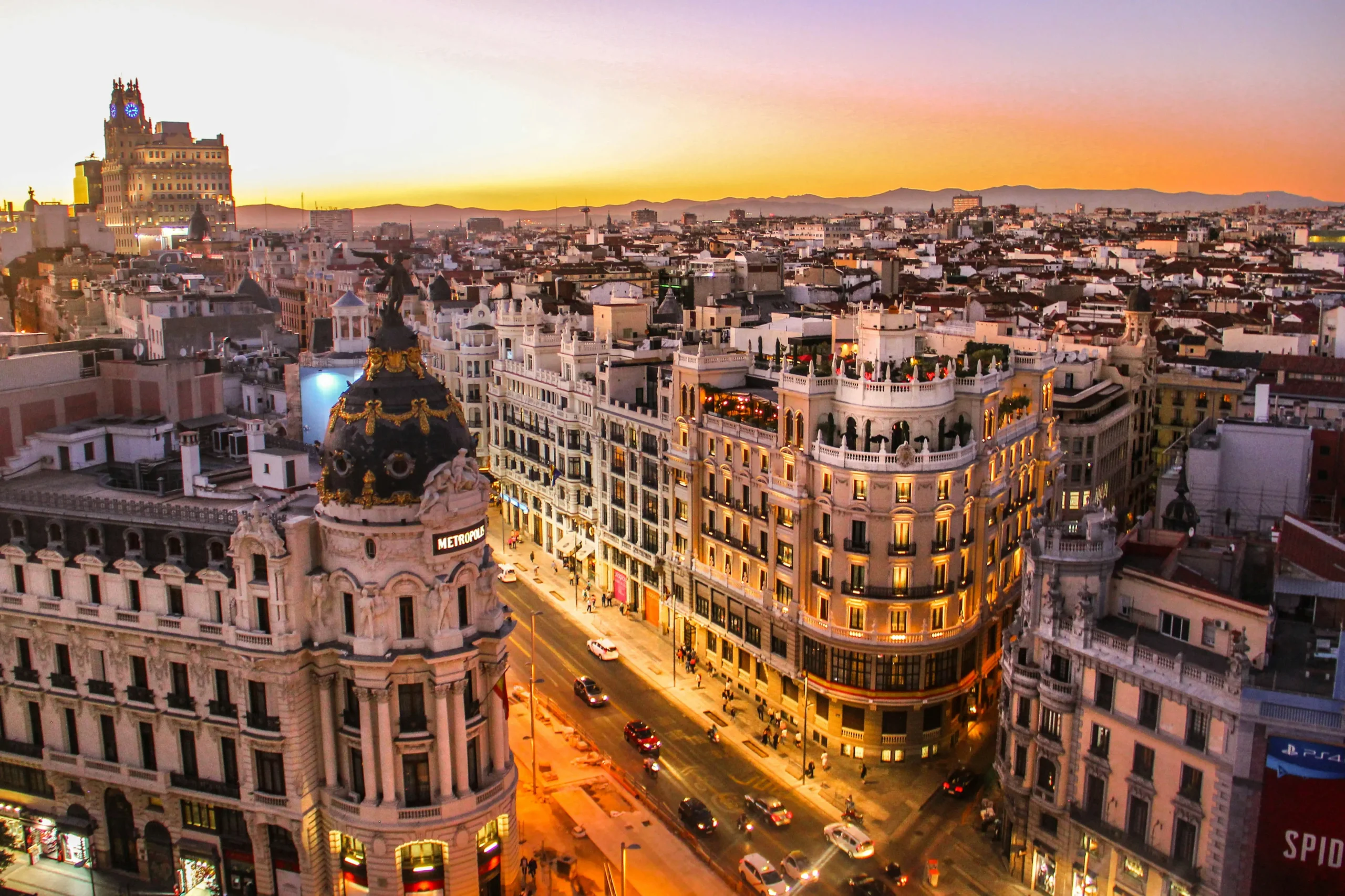 Vue panoramique de Madrid au coucher du soleil avec l'édifice Metrópolis et la Gran Vía, deux symboles emblématiques de la capitale espagnole.