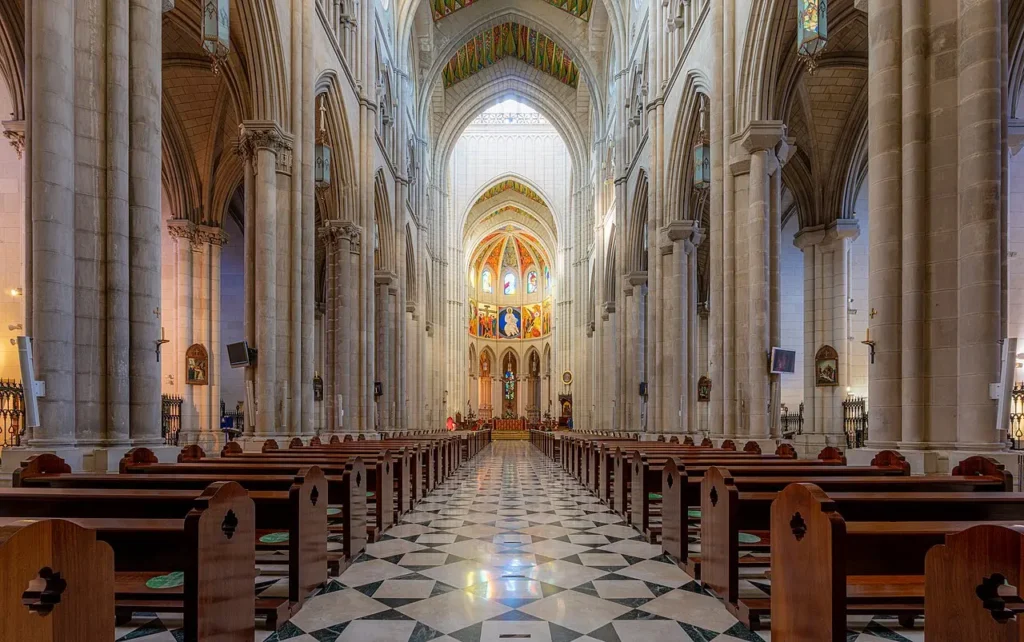 Nef principale de la cathédrale de l'Almudena à Madrid, avec ses voûtes colorées et son autel central.