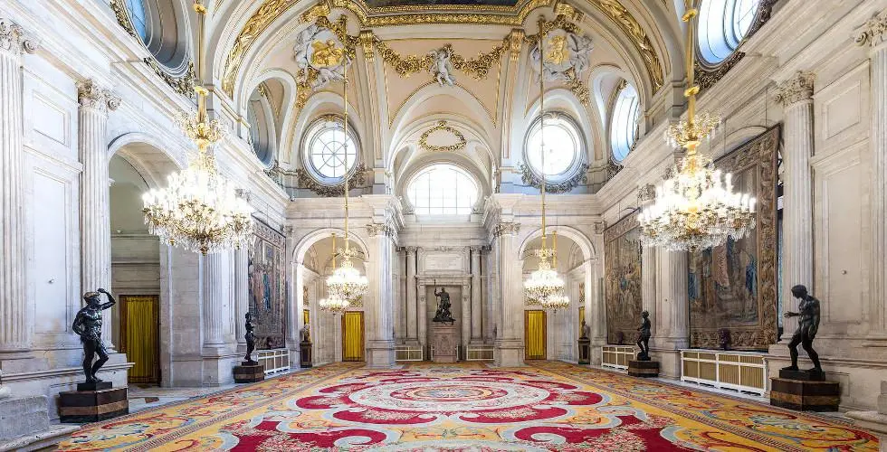 Salon des Colonnes du Palais Royal de Madrid, avec ses colonnes de marbre, ses lustres et son décor majestueux.